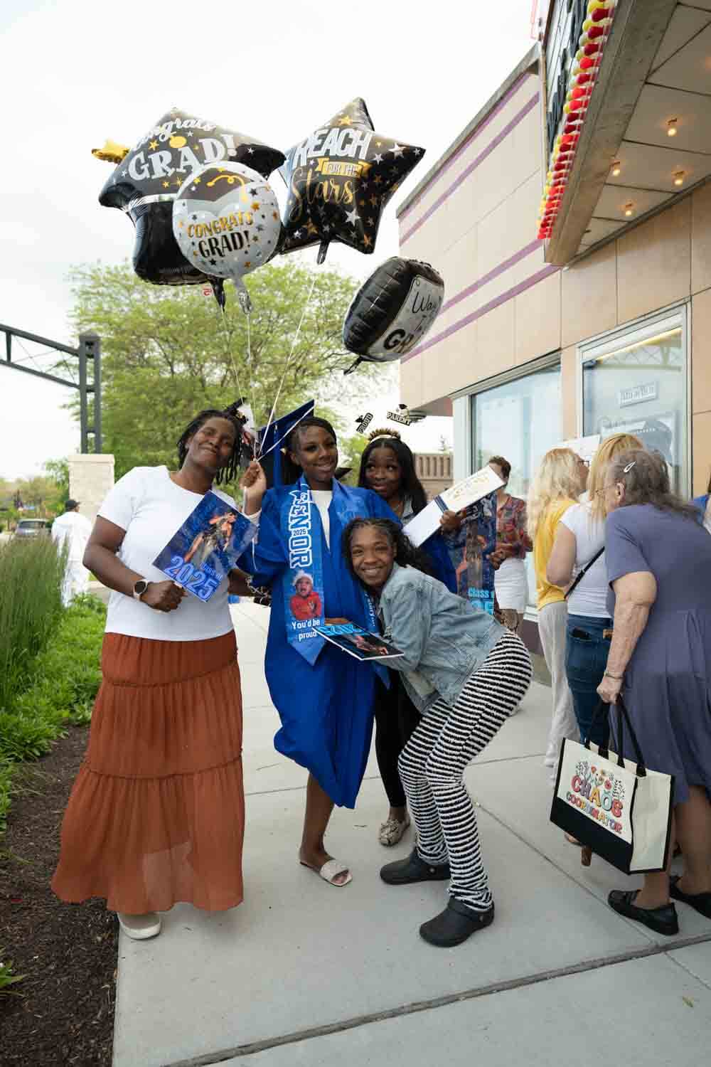 Un graduado con toga y birrete azul sostiene globos de celebración